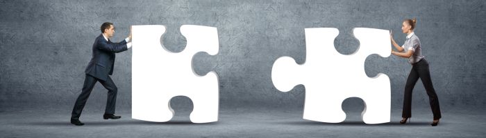 Twee personen die ieder een puzzelstukje tegen elkaar aanduwen